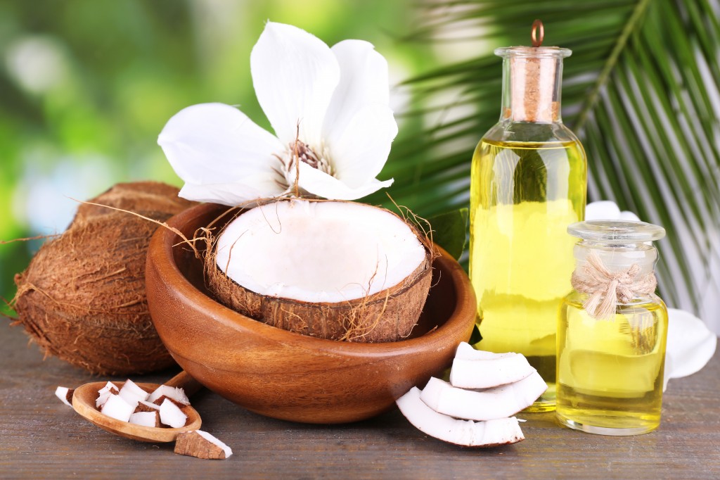 Coconuts and coconut oil on wooden table, on nature background